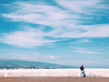 Friends standing on beach against sky