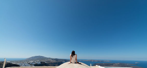 Rear view of woman against clear blue sky