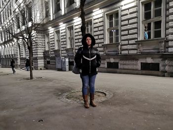 Full length portrait of woman standing against building in city