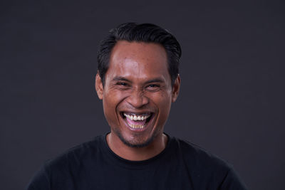 Portrait of smiling young man against black background