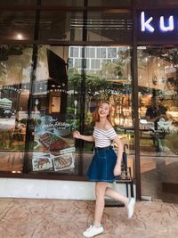 Portrait of young woman looking through window at store