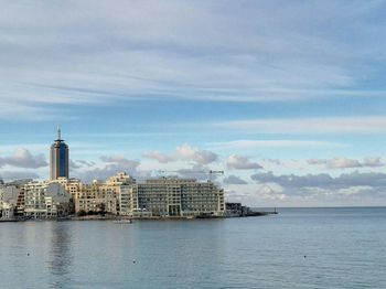 Sea by cityscape against sky