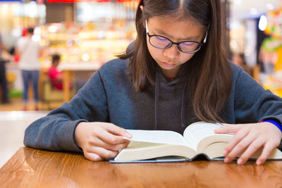 Close-up of teenage girl reading book at table