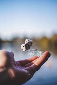 Close-up of person throwing dice against sky