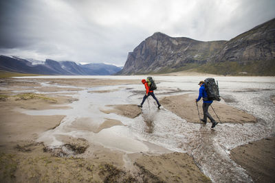 Two backpackers cross streams in akshayak pass, baffin island.