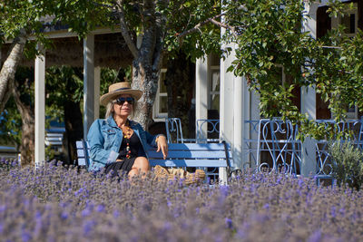 Portrait of happy woman sitting on purple flowering plants
