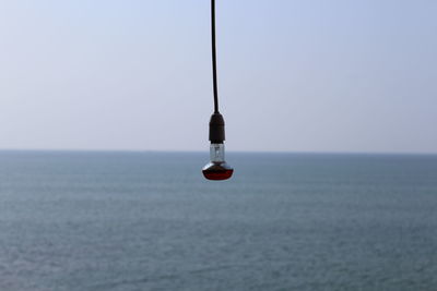 Close-up of boat hanging in sea against clear sky