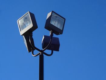 Low angle view of telephone pole against clear blue sky