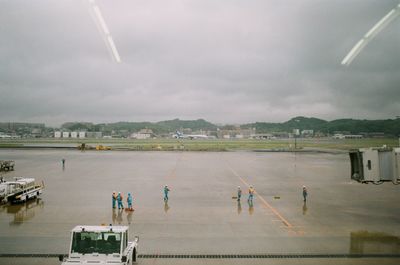 People on airport runway against sky