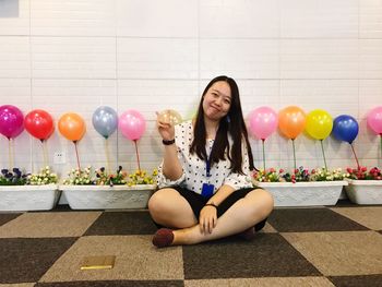 Portrait of smiling young woman holding balloons