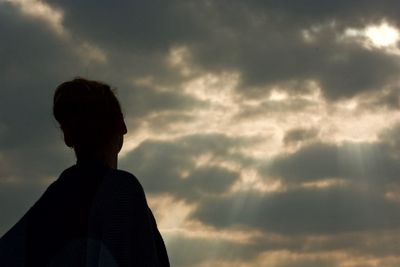 Low angle view of silhouette woman against cloudy sky during sunset