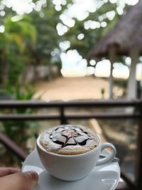 Close-up of hand holding coffee cup on table