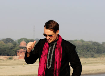 Young man standing on field against clear sky