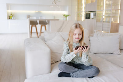 Portrait of smiling woman sitting on bed at home