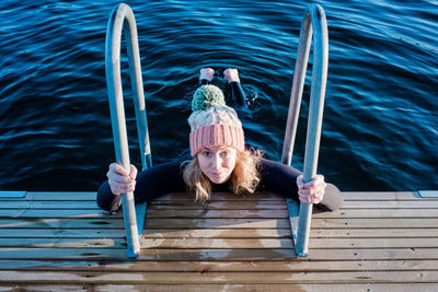 Woman looking up holding onto steps whilst cold water ice swimming