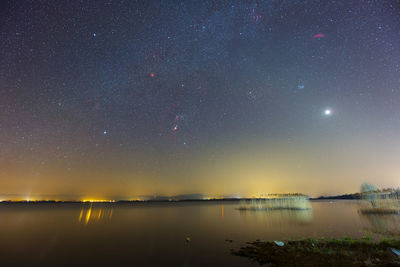 Scenic view of lake against sky at night