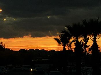 Silhouette palm trees against orange cloudy sky