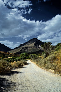 Road leading towards mountains against sky