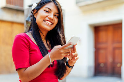 Portrait of smiling young woman using mobile phone