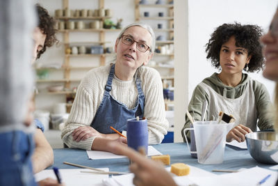 Female students listening sitting at table in art class