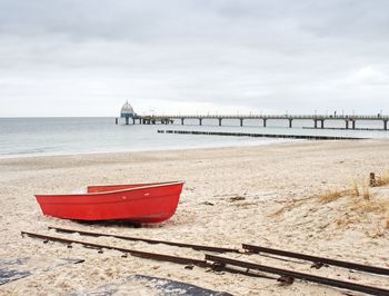 Deck chairs on beach against sky