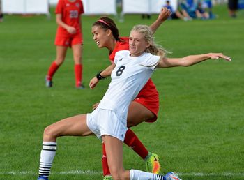 Full length of friends playing soccer on field