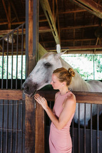 Woman standing by horse in stable