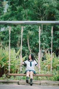 Woman sitting on swing in park