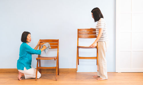 Full length of mother and daughter standing on floor at home