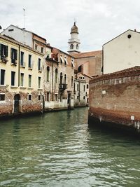 Canal amidst buildings against sky in city