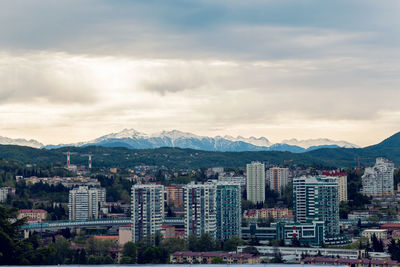  city of sochi overlooking the houses and the snow capped mountain in the background