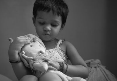 Black and white portrait of a cute baby girl playing with a soft toy