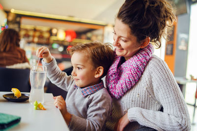 Smiling woman sitting with son at table in restaurant