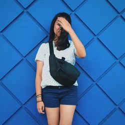 Woman standing against blue wall