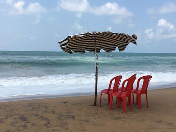 Deck chairs on beach against sky