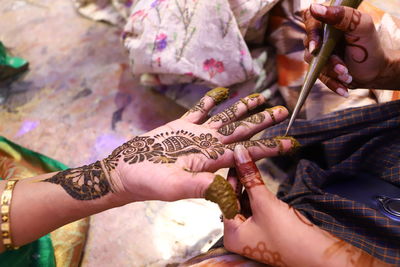 Cropped hand of woman applying henna tattoo at home