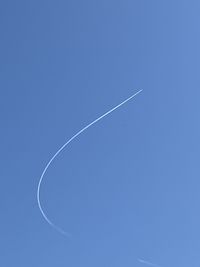 Low angle view of vapor trail against clear blue sky