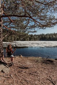 Woman sitting on shore by lake