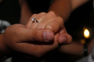 Cropped image of couple holding hands in darkroom