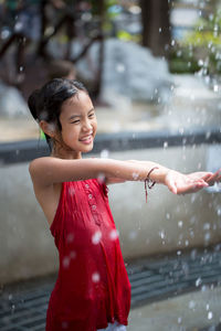 Smiling girl standing at fountain in park
