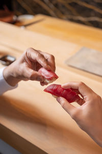 Two person holding sushi with hands