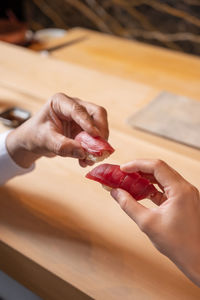 Cropped hands of woman making heart shape on table