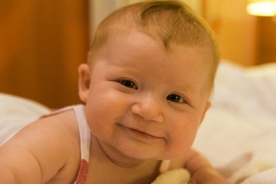 Close-up portrait of smiling baby lying on bed at home