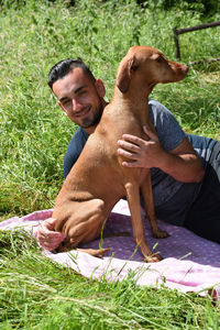 High angle view of man lying with vizsla on picnic blanket at park