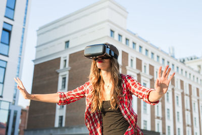 Woman wearing virtual reality simulator against building