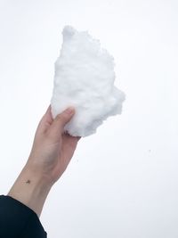 Close-up of hand holding ice against sky