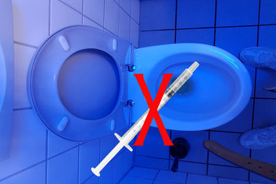 Digital composite image of syringe with cross sign over toilet bowl in bathroom
