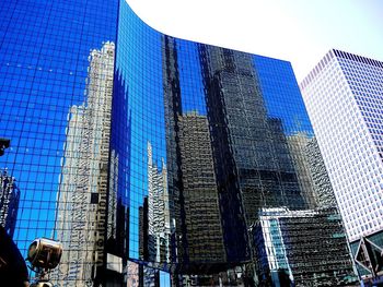 Low angle view of skyscrapers against blue sky