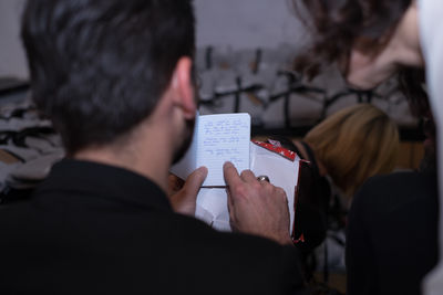 Rear view of man pointing on notepad