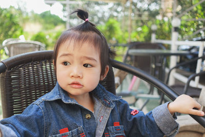 Close-up of cute baby girl sitting on chair outdoors